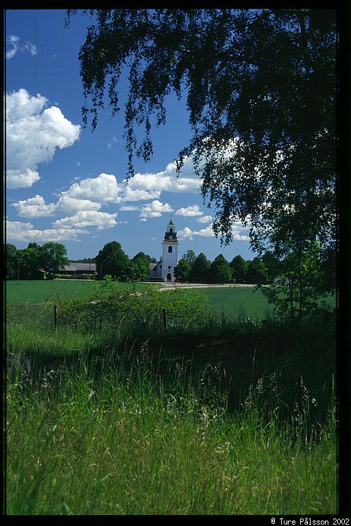 Rystad church, grass and foilage in foreground